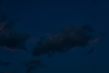 A large, dark cloud floats in a deep twilight sky, tinted with faint pink light, creating a minimalist, moody scene with ample space for text.
