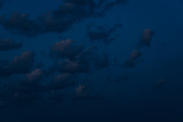 A large, dark cloud floats in a deep twilight sky, tinted with faint pink light, creating a...