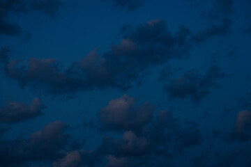 A large, dark cloud floats in a deep twilight sky, tinted with faint pink light, creating a...
