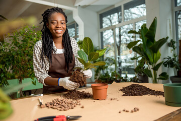Smiling flower shop assistant planting flowers and feeling good