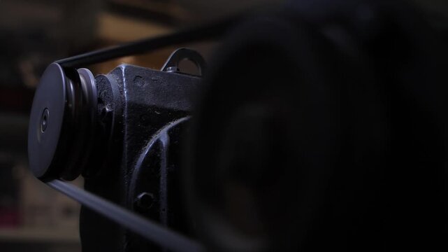 Industrial metal pulley, rubber belt in motion in old workshop machinery system.