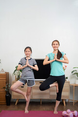 Mother and daughter practicing yoga poses in a cozy living room