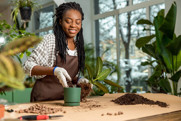 Florist putting soil into the flower pot while planting the flowers