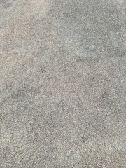 A detailed close-up of a fine sand or gravel surface, featuring natural speckled texture and earthy tones.