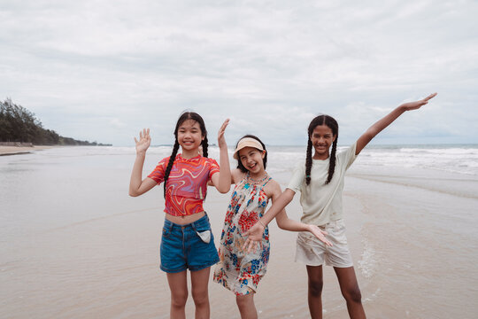Friends beach enjoying summer fun. Asian and multicultural kids smiling, pointing, and laughing together with joy and freedom. - Powered by Adobe