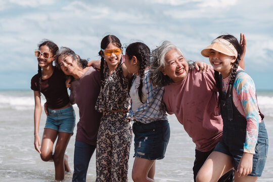 Happy Asian family group, senior women and kids enjoying playful beach. Celebrating love, wellness, and multi generational togetherness by the sea.