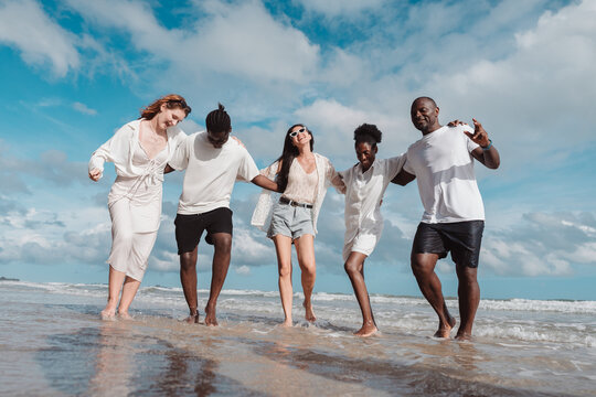 Happy diverse group of friends together on the beach, Active friendship, summer fun, positivity, and joyful lifestyle by the sea. - Powered by Adobe