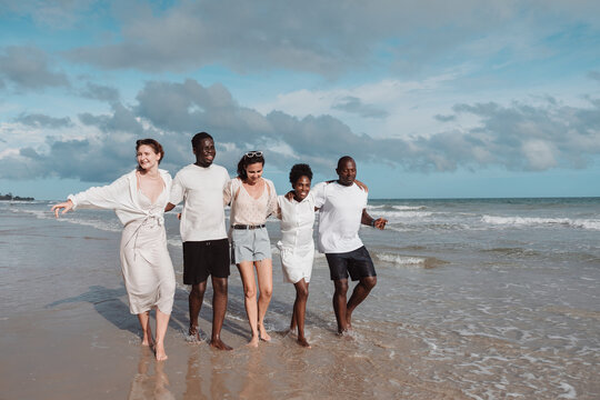 Diverse group of friends enjoying active lifestyle by dancing and splashing water on the beach. summer fun, movement, and joyful friendship. - Powered by Adobe