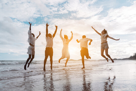 Happy diverse group of friends jumping on the beach, enjoying freedom, movement, and summer fun. active lifestyle, togetherness, and joyful friendship.