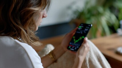A woman is using a smartphone to check market data - Powered by Adobe