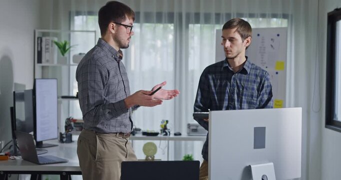 Team adult male engineer collaborate on robotic hand project using AI code solutions machine learning at tech workspace. Artificial intelligence interface, collaboration support prototype development.