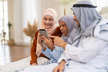 Muslim family learning online use tablet for homeschool education, daughter engaged in e-learning while parents guide with modern knowledge digital, online entertainment and muslim kids development