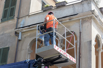 Operaio edile su piattaforma aerea che restaura la facciata di un edificio storico
