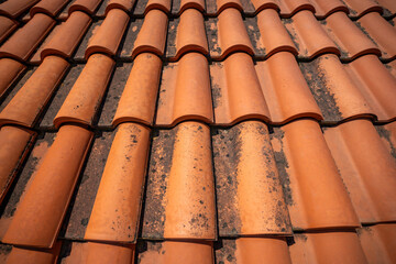 Close-up of red ceramic roof tiles in an old Mediterranean town. Traditional roofing, architecture, and construction texture.