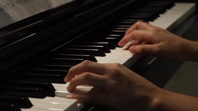 A close-up of hands gracefully playing a piano, showcasing the black and white keys under soft lighting.