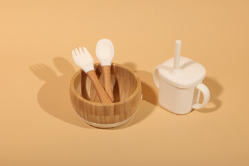 Minimalist Baby Feeding Set: Bamboo Bowl, Silicone Utensils, and Sippy Cup on Beige Background