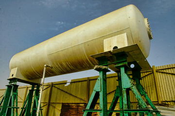 A large white tank is on a stand in front of a building