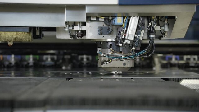 A metalworking pressing machine processes a sheet of metal