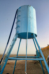 A blue water tank is on a beach