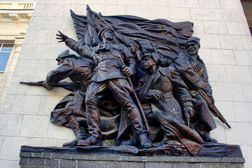 A statue of soldiers in uniform with a flag in the background