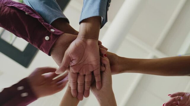 Closeup of diverse business people stacking hands in office