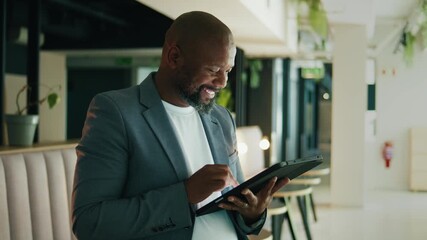 Bald black businessman smiling and using tablet PC in modern office - Powered by Adobe