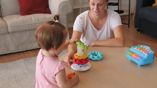 Mother and daughter playing with colorful stacking rings toy