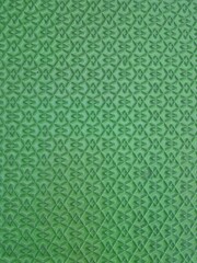 Vibrant green abstract background with a repeating geometric diamond pattern. Close-up of a textured surface for design.