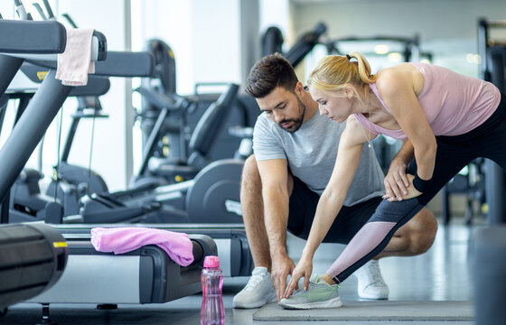 Personal fitness trainer supervising middle aged woman during gym workout.
