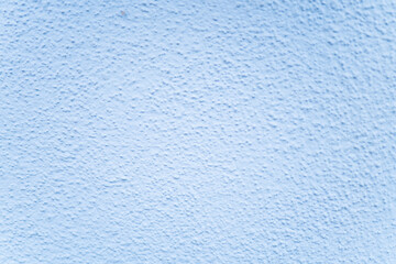 Soft blue texture of a stucco wall inviting calmness on a sunny day