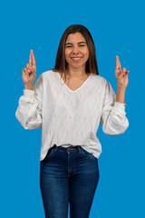 Young woman crossing fingers wishing for good luck on blue background