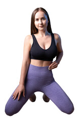 A young healthy girl in a sports top and leggings poses in the studio against a black background.