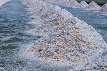 Pyramids of sea salt ready to be harvested in a salt farm at sunrise. Used as a seasoning in food,...
