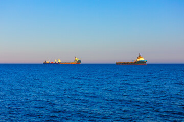 Cargo ships traverse the vast expanse of the ocean. Tranquil scene of the open sea, with two ships...