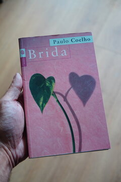 Hand Holding Paulo Coelho's "Brida" Book with Heart Leaf Cover
