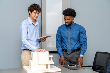 Architects and designers work presenting and discussing house model in office meeting. The...