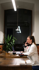 Beautiful woman in a white blazer working on a laptop in a café