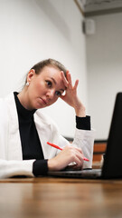 Beautiful woman in a white blazer working on a laptop in a café