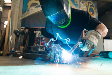 worker in protection mask welding metal at factory