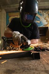 producing worker is sharpening a metal plate while sparks fly while putting on safety gloves in in-depth and space