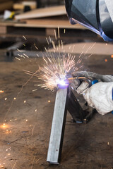 Competent industrial worker dressed in protective clothes grinding metal construction using...