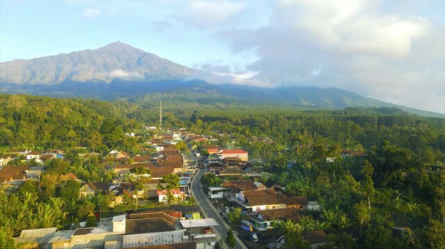 A beautiful village lies peacefully beneath Mount Arjuna, partially obscured by morning clouds.