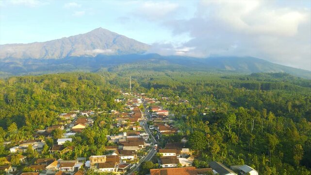 A beautiful village lies peacefully beneath Mount Arjuna, partially obscured by morning clouds.