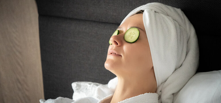 young woman getting eye nature treatment by cucumber at luxury spa resort. Wellness and healing concept.