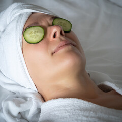 young woman getting eye nature treatment by cucumber at luxury spa resort. Wellness and healing...