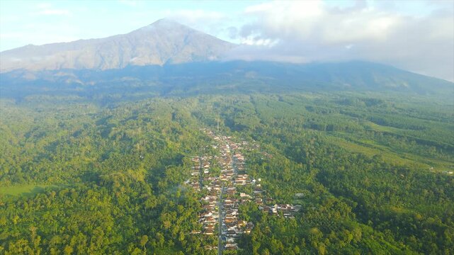 A beautiful village lies peacefully beneath Mount Arjuna, partially obscured by morning clouds.
