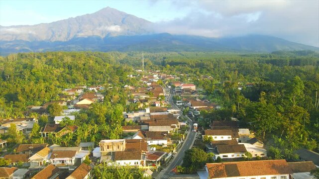A beautiful village lies peacefully beneath Mount Arjuna, partially obscured by morning clouds.