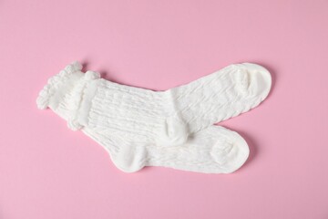 Pair of comfortable white socks on pink background, top view