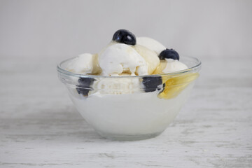 Creamy ice cream with blueberries and honey in a glass bowl