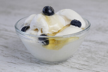 Creamy ice cream with blueberries and honey in a glass bowl